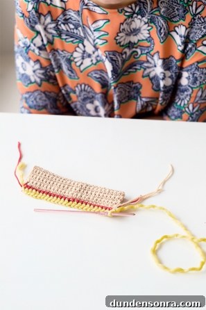Someone sewing something beige, red, and yellow