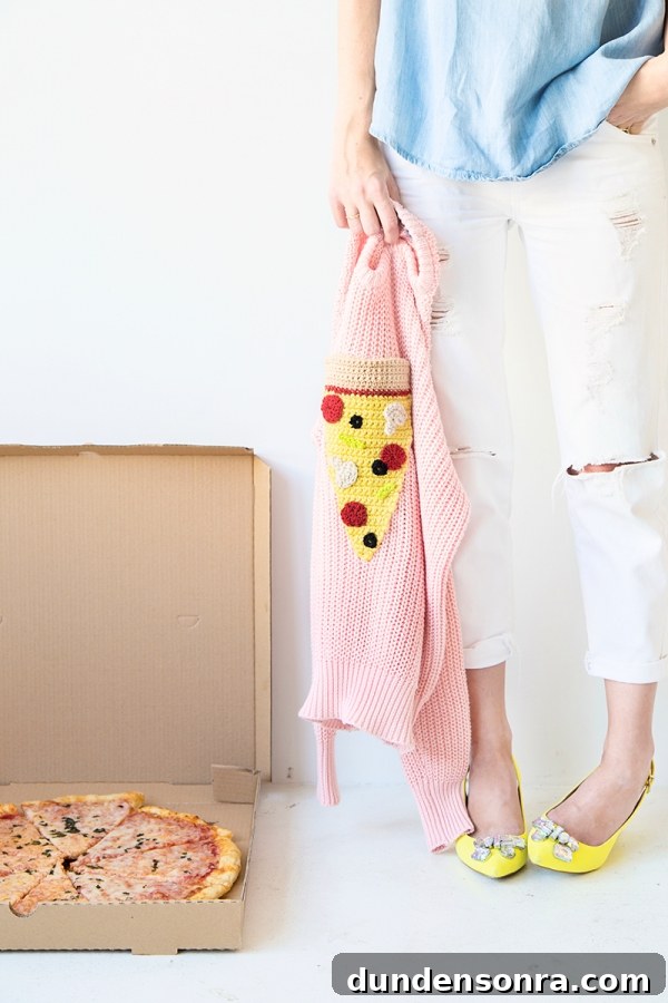 Someone holding a pizza sweater and a box of pizza next to it