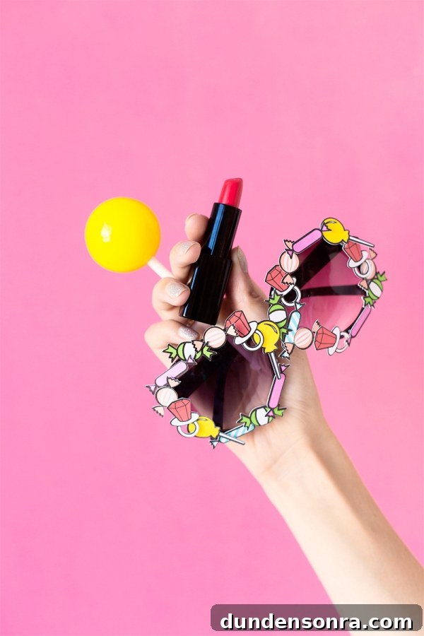 Someone holding glasses, lipstick, and a yellow ball