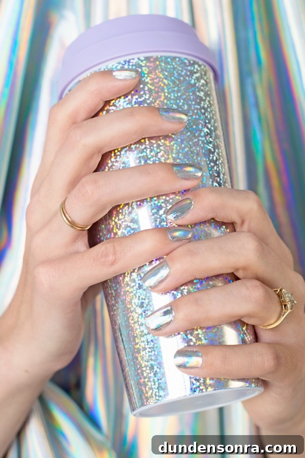 A woman holding a silver cup with silver nails