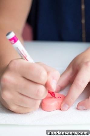 DIY Conversation Heart Rings: Make Cute Candy Heart Jewelry at Home 7 Someone writing on a heart item