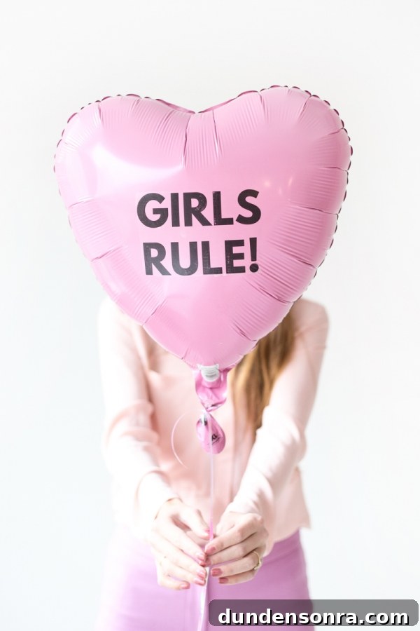 Someone holding a pink balloon that says girls rule