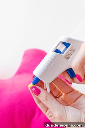 Someone gluing something on pink fabric