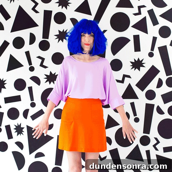Someone posing in a costume in front of a patterned wall