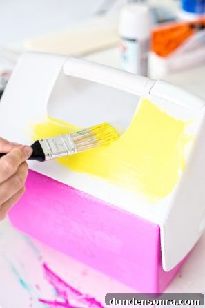 Someone painting a cooler yellow and pink