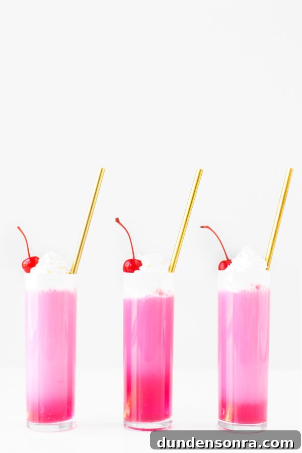 Three glasses with gold straws and pink liquid 