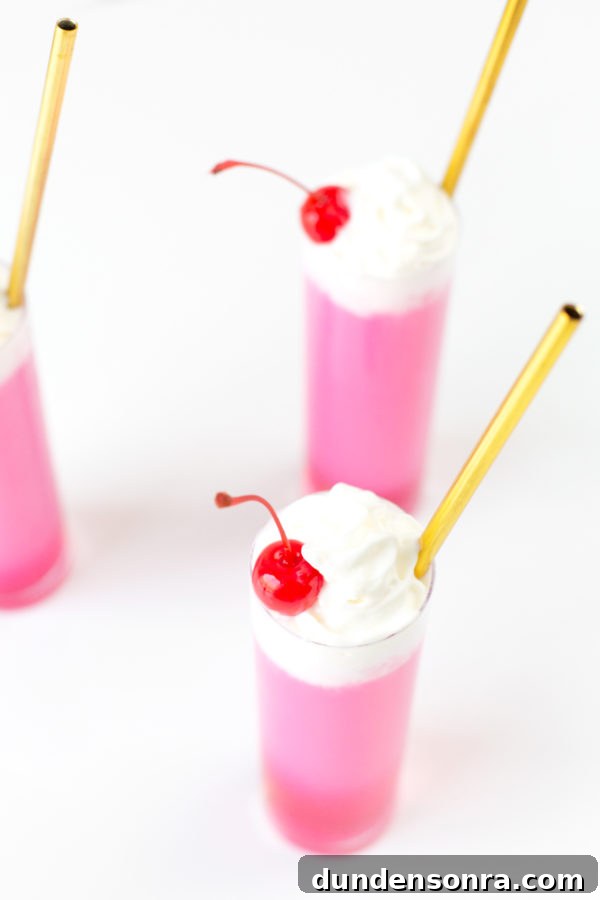 Three glasses with gold straws and pink liquid 