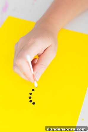 Someone putting black dots on a yellow paper
