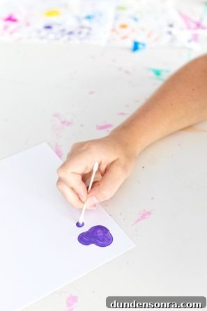 Someone painting purple on a paper