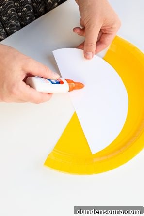 Someone gluing white paper on a yellow plate