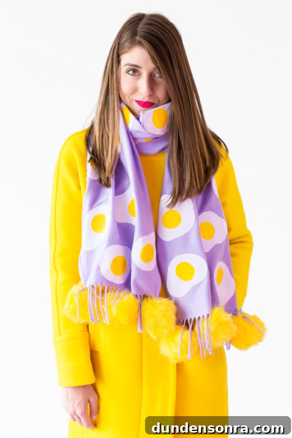 A woman wearing a purple scarf with eggs on it and a yellow jacket