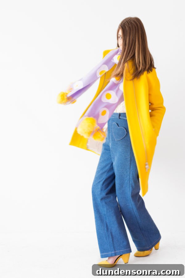 A woman wearing a purple scarf with eggs on it and a yellow jacket