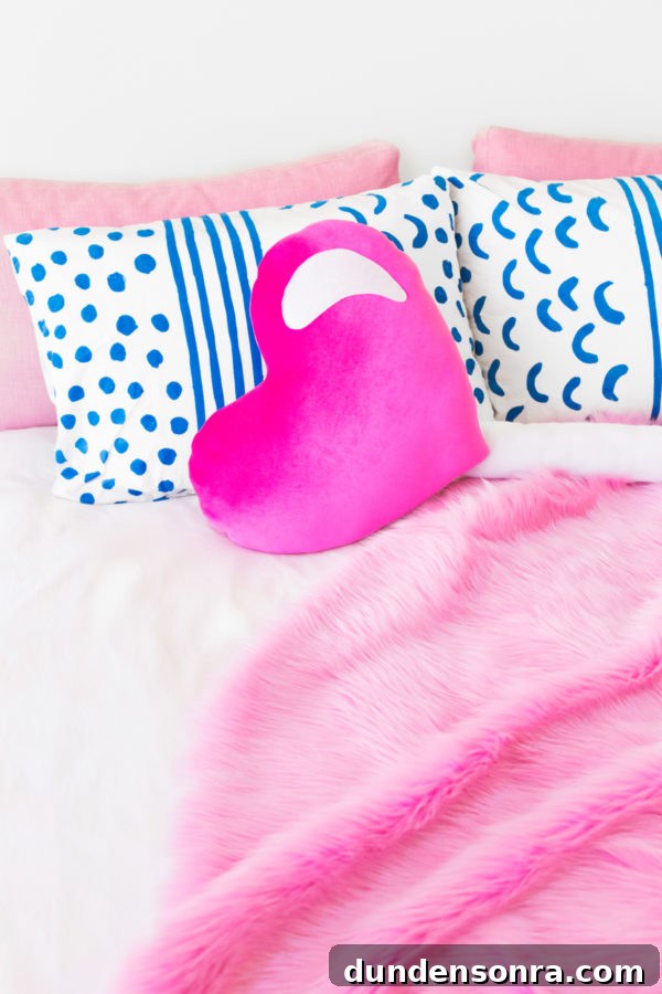 A bed with pillows and a pink blanket