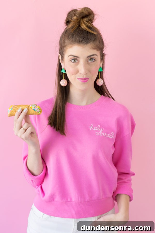 DIY Embroidered Sweatshirt: Simple Embroidery Hack for Perfect Stitches 4 A woman in a pink crewneck holding a cannoli