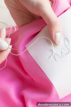 DIY Embroidered Sweatshirt: Simple Embroidery Hack for Perfect Stitches 8 Someone sewing something onto a pink shirt