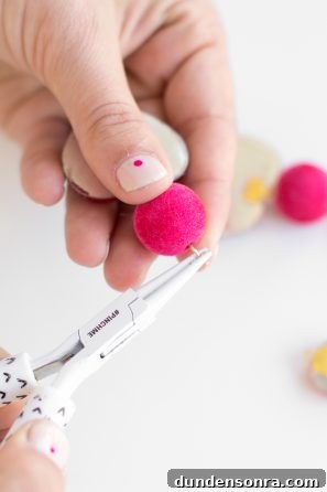 Someone holding a tool and a pink felt ball