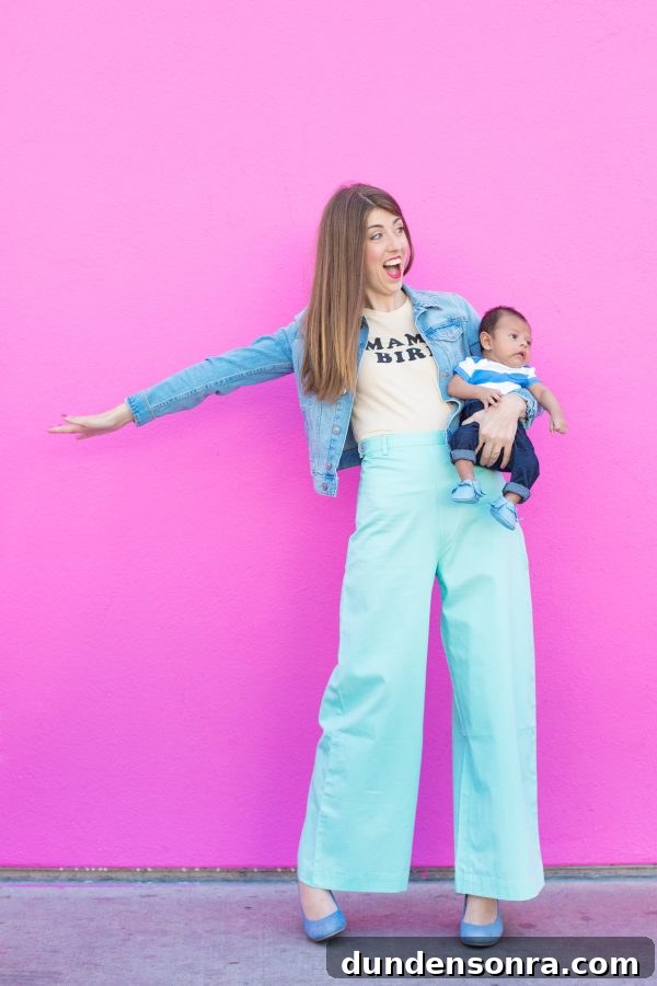 A woman holding a baby in front of a pink wall