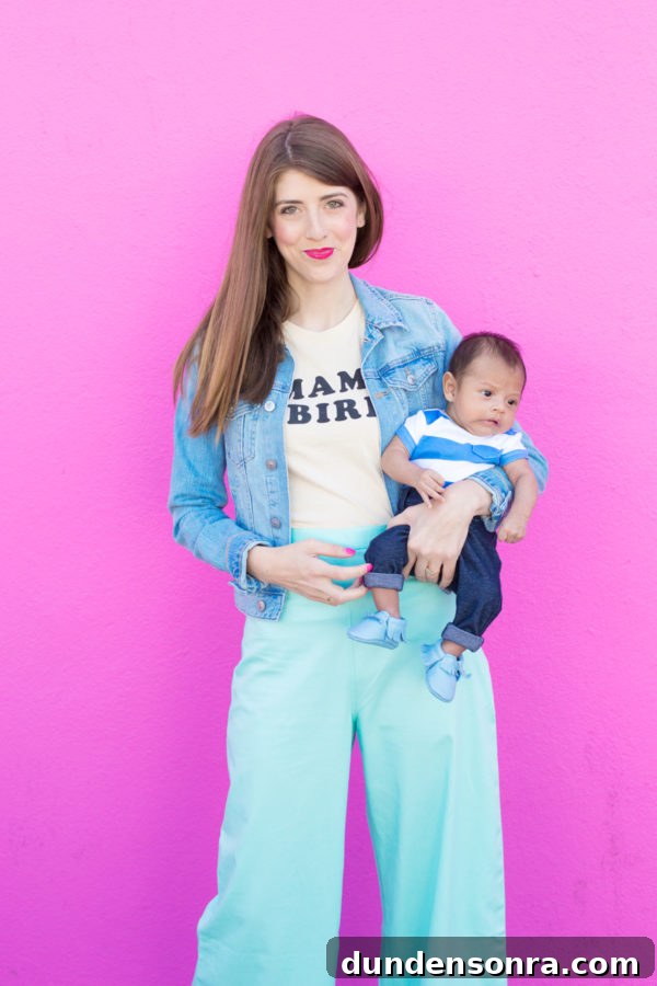 A woman holding a baby in front of a pink wall