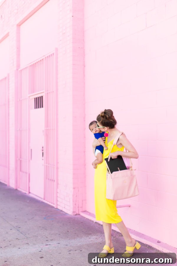Someone holding a baby in front of a pink wall