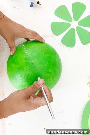 How to Make Giant Foam Fruit Decorations for Parties 7 Someone cutting a green sphere