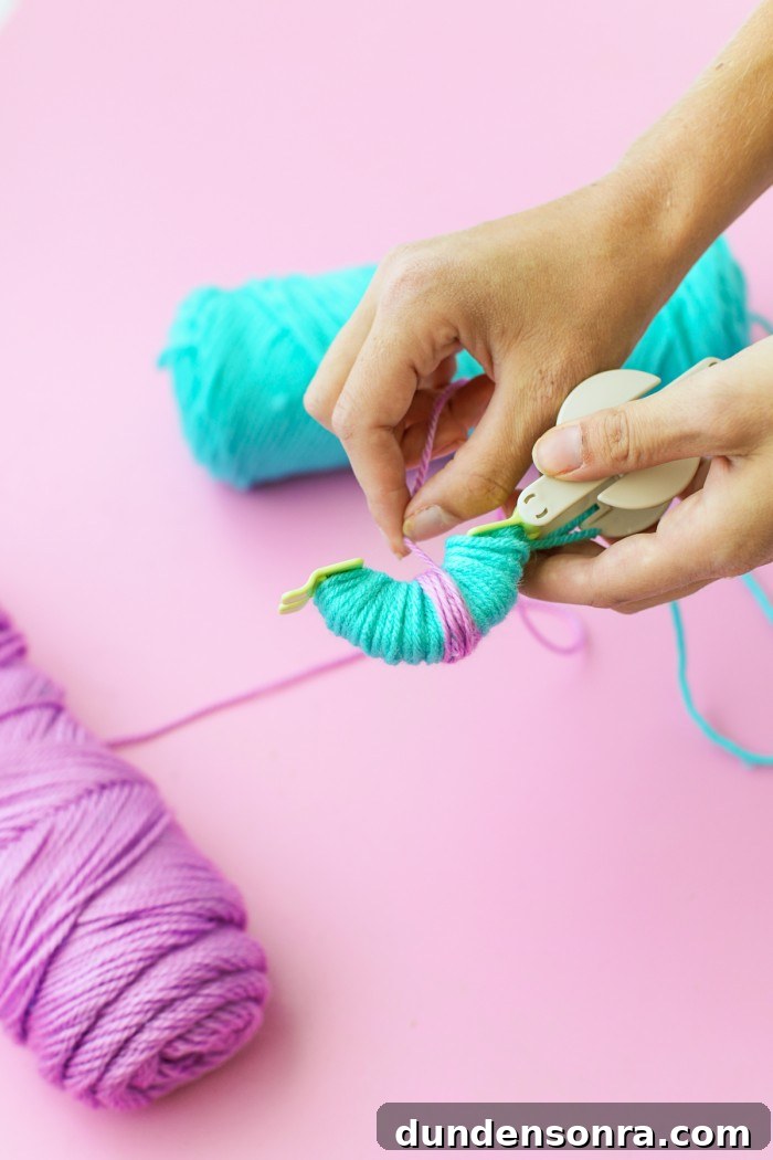 Blue and purple yarn wrapped around a Pom Pom maker