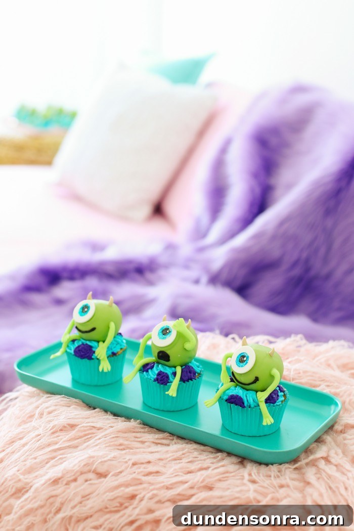 Mike wazowski Monsters Inc cupcakes sitting on a teal tray on a pink faux fur blanket