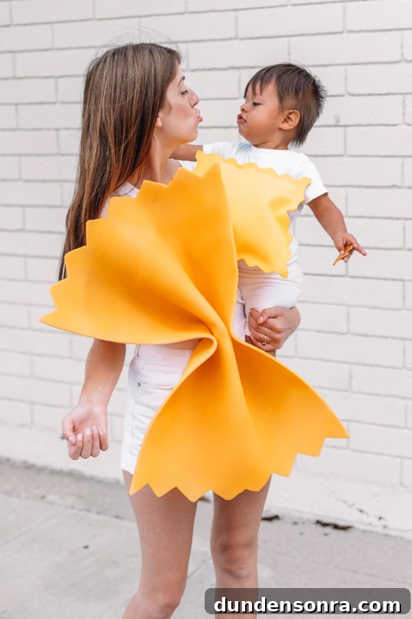 A woman holding a baby dressed as pasta