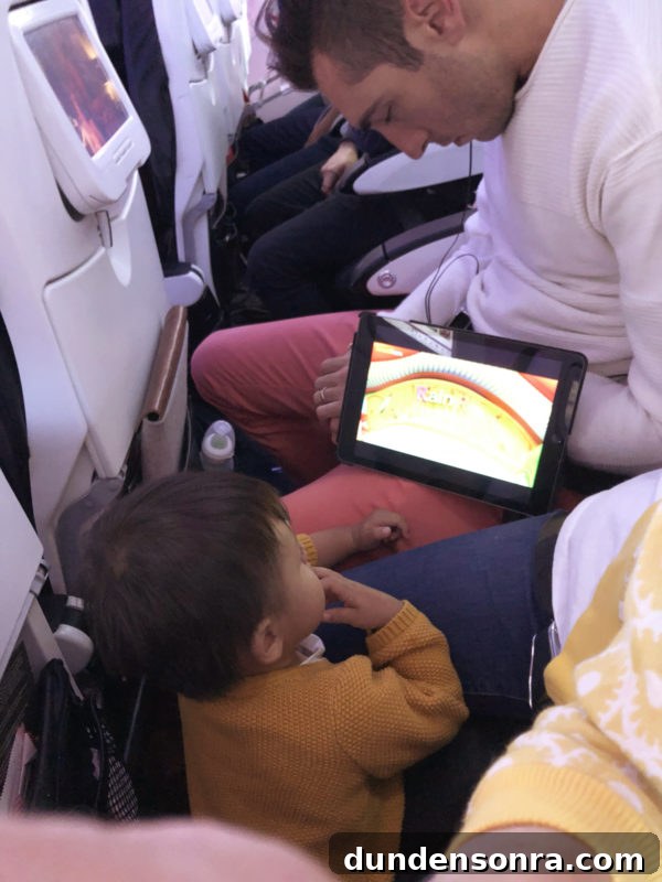 Flying With a Baby or Toddler: Tips, Gear & Plane Activities 8 A little kid on a plan with an ipad