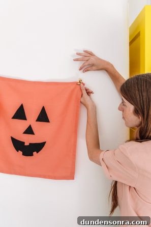 A person holding a sheet that looks like a pumpkin