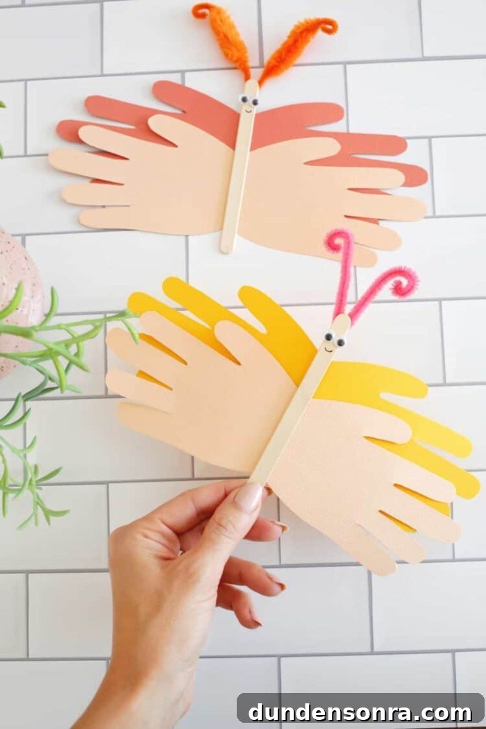 24 Fun Bug Crafts and Activities for Kids to Try Today 12 Hand holding butterfly handprint craft.