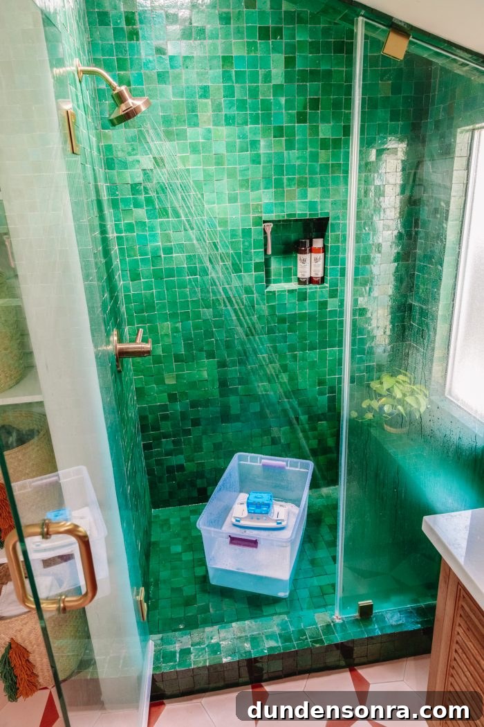A green tiled shower with a soap bucket