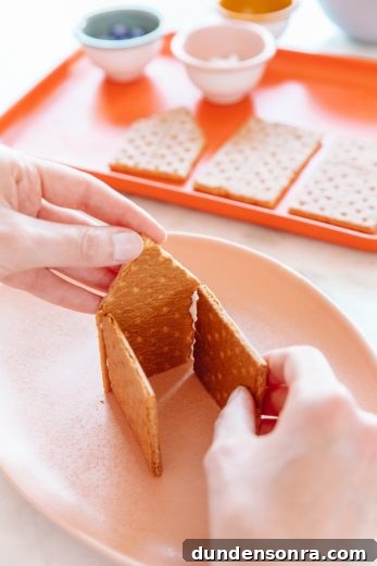 Edible Haunted Houses: Halloween Candy House Ideas and Guide 11 Someone making a house with graham crackers