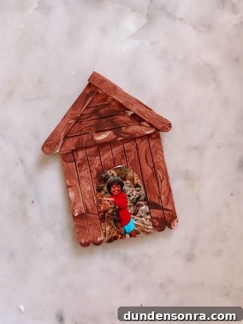 A wooden house ornament with a picture of a boy in the middle