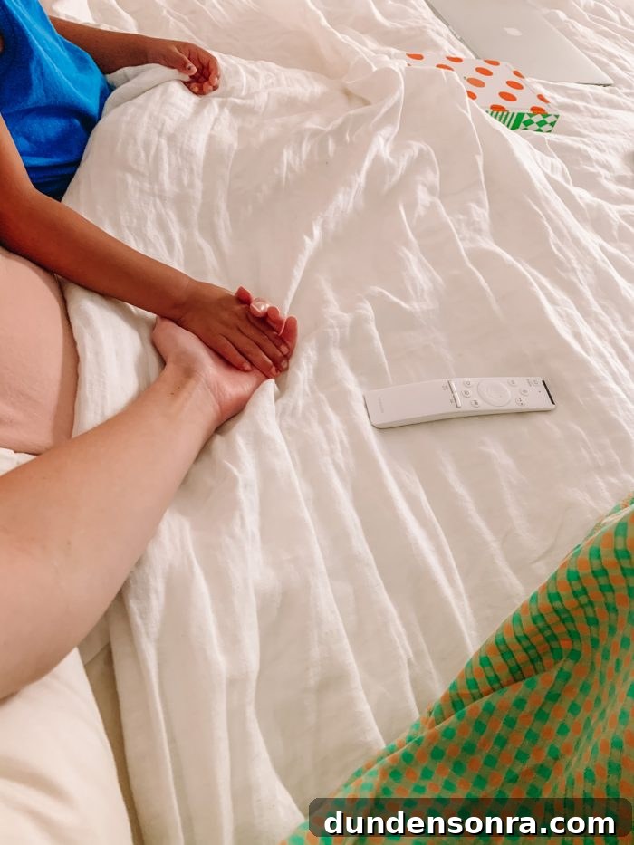 Two people holding hands on a bed
