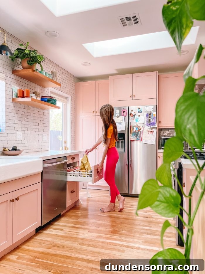 Sustainable Paper Towel Alternatives: Practical Ways to Eliminate Disposable Towels 6 Woman in pink kitchen pulling towel out of drawer with a plant in the foreground