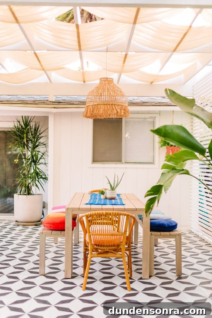 Black and white tile patio with dining table and colorful pillows with a pergola above it