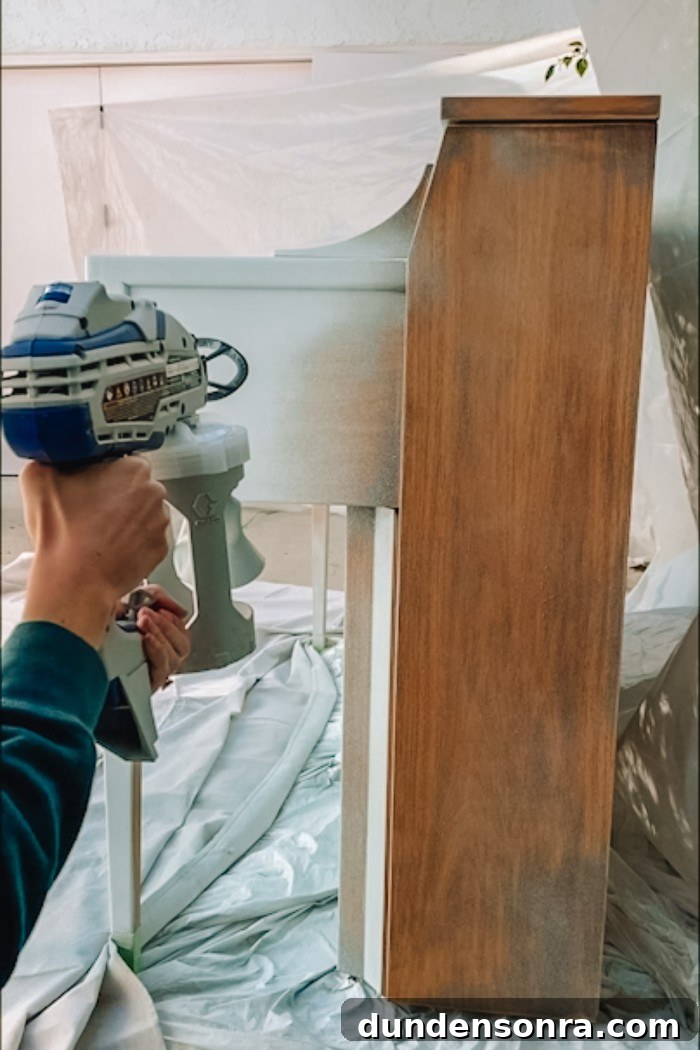 Painting the side of a wood piano with a paint sprayer