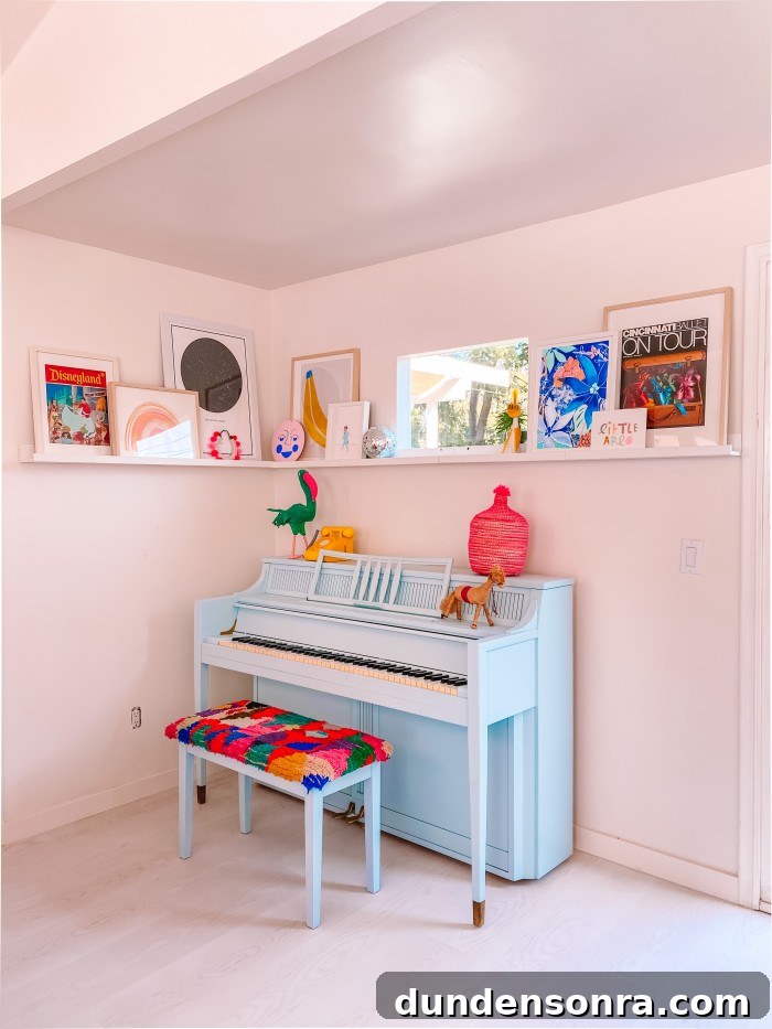 Blue piano in a corner with art on a ledge above and a window