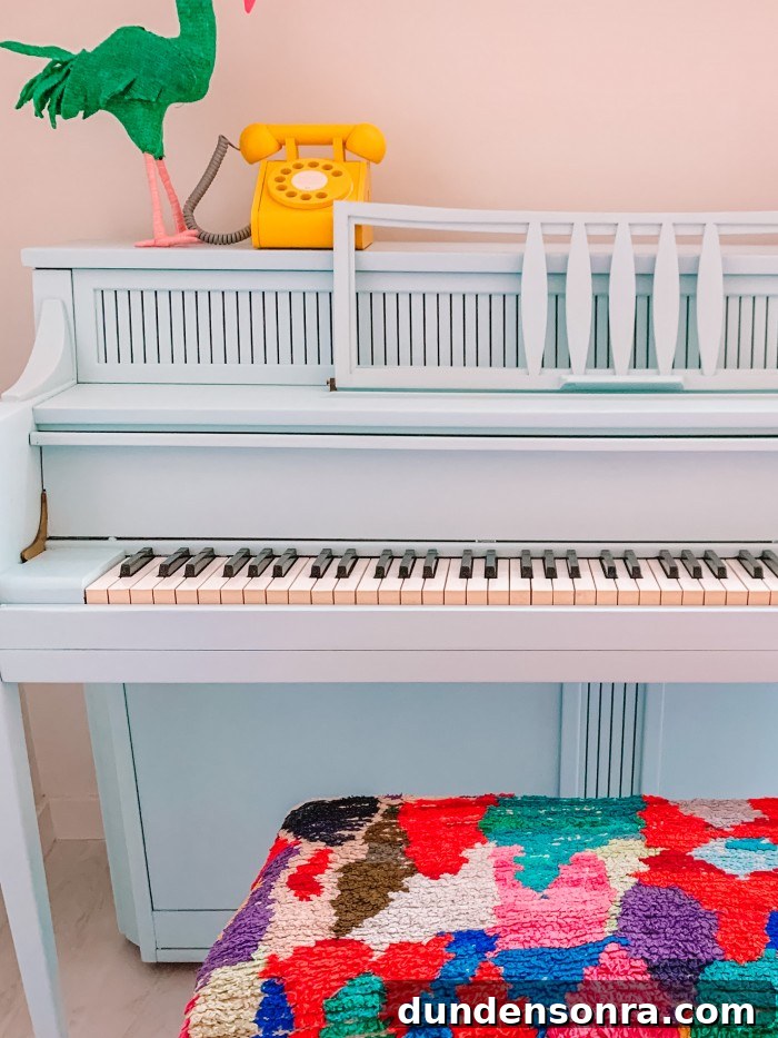 Blue painted piano with a colorful bench and a yellow phone on top