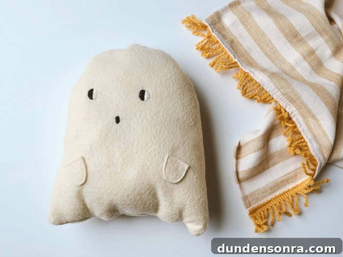 Top Halloween Home Decor Ideas to Transform Your Space 19 Plush ghost pillow next to a striped blanket on white background