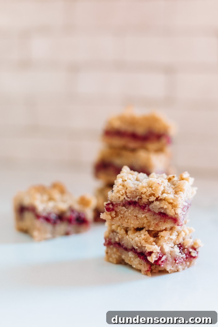 Raspberry Bars stacked in front of white tile