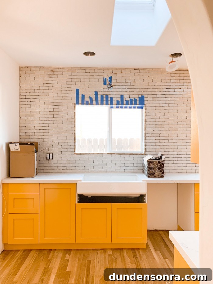 Yellow orange kitchen cabinets with white zellige tile above