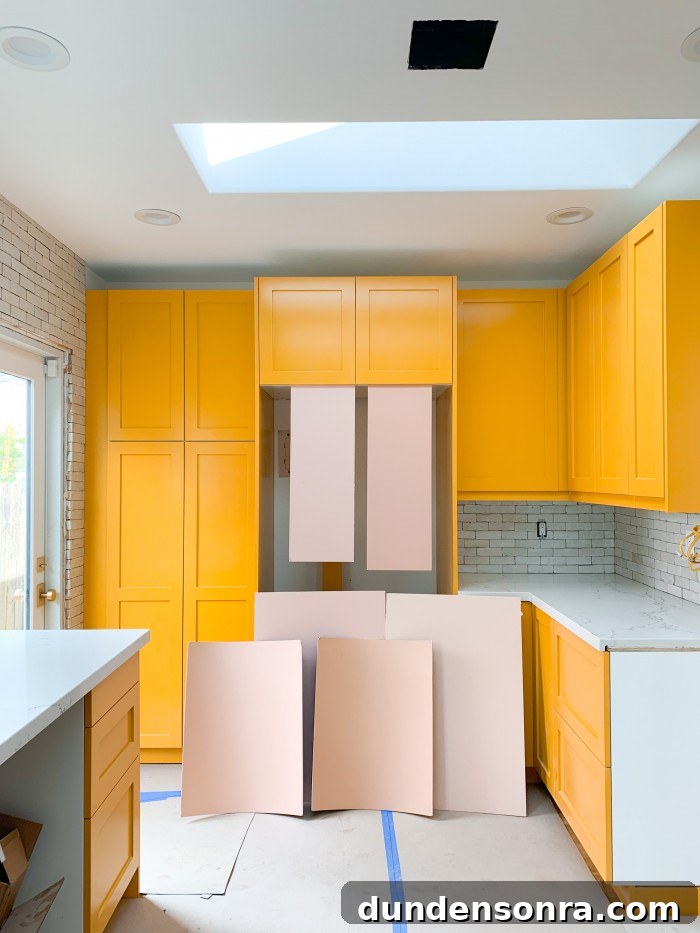 Yellow orange kitchen cabinets with pink paint swatches in front