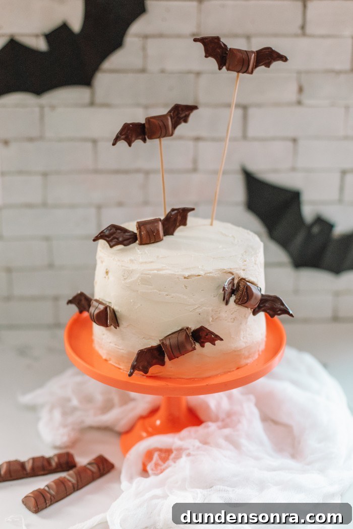 White cake with chocolate bats on it on an orange cake stand