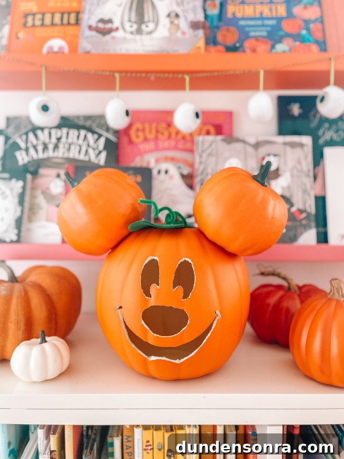 Mickey Mouse Pumpkin Carving and Decorating Guide 13 Mickey pumpkin in front of Halloween books and eye ball garland