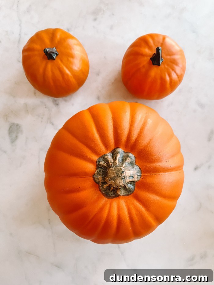 Mickey Mouse Pumpkin Carving and Decorating Guide 4 One large pumpkin with two small pumpkins above it on marble table