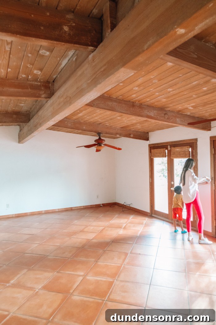 Mom and child in empty house with terracotta floors and wood beamed ceilings