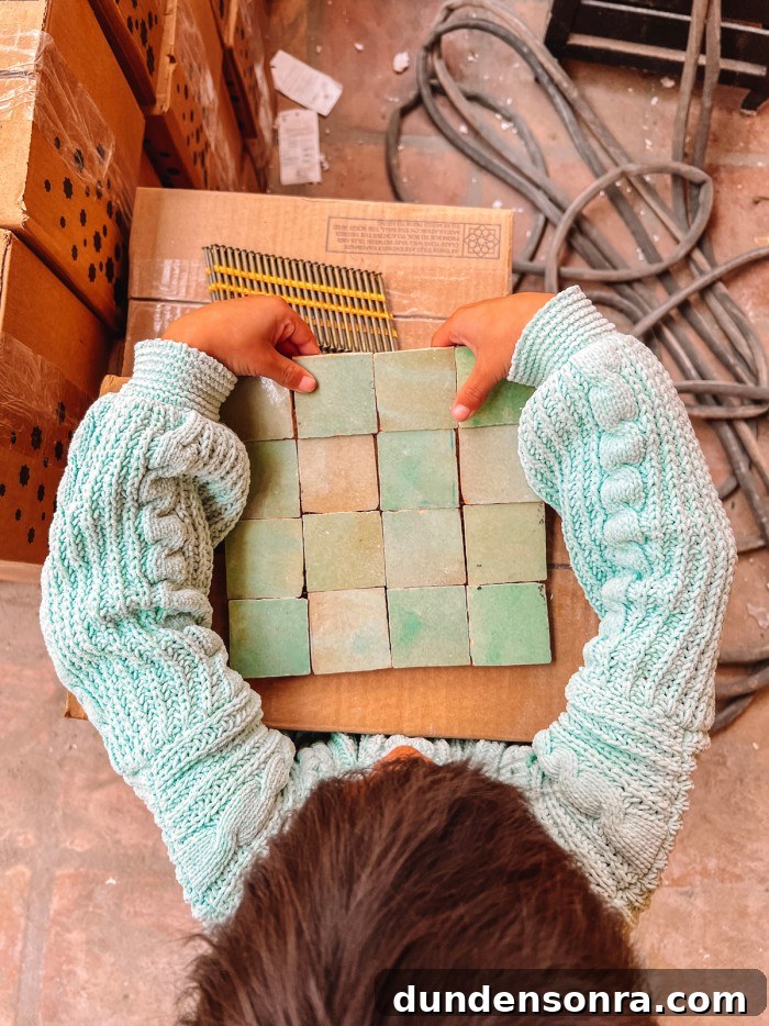 Child holding mint green zellige tile in a mint green sweater