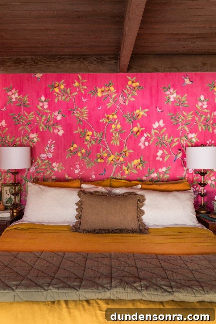 mustard and olive bed with pink wallpaper behind and lamps on nightstands