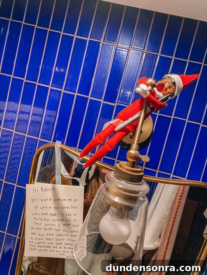 Elf on the shelf hanging on sconce in blue bathroom